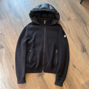 Moncler Hooded Down Cardigan - Moncler Hooded Down Cardigan i bra skick, sömmen i högra armhålan har lossnat lite men syns ej vid användning. Väldigt ovanlig cardigan, slutsåld och produceras inte längre. Storlek M passar M, nypris 9000 mitt pris 4300 men billigare vid snabb affär
