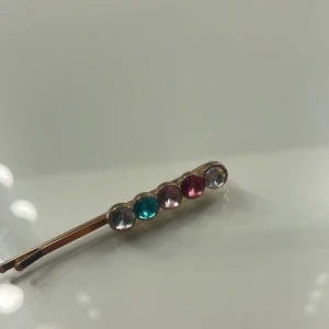 Hårspänne med färgglada stenar - Säljer ett superfint hårspänne med glittriga stenar i olika färger.