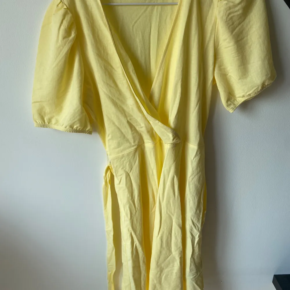 Säljer en superfin gul omlottklänning från Gina Tricot. Den har korta ärmar och ett knytband i midjan som ger en snygg passform. Perfekt för sommardagar eller en festlig kväll! 💛. Mekot.