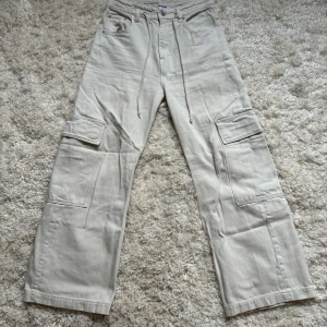 Ljusa cargo liknade jeans - Beige/vita cargo liknande jeans med lite utsvängda ben från Weekday. Knappt använda och justerbar midja. 