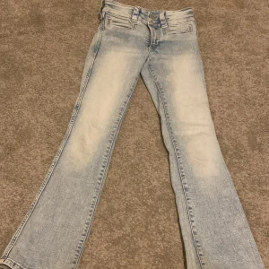 Ljusblå bootcut jeans - Säljer ett par ljusblå bootcut jeans med en snygg tvättad look. De har en klassisk femficksdesign och stängs med dragkedja och knapp. Perfekta för en avslappnad stil!