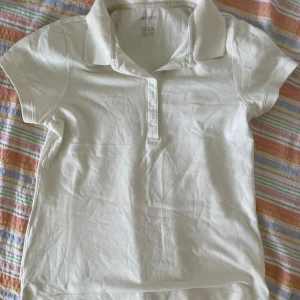 Vit kortärmad pikétröja från Esmara - Säljer en klassisk vit pikétröja från Esmara. Den har en stilren krage och knappar framtill. Perfekt för en avslappnad men ändå snygg look. Tröjan är i bra skick och passar till både vardag och lite mer uppklädda tillfällen.