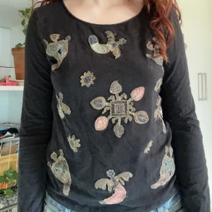 Långärmad svart tröja från kenzo - Långärmad svart tröja med broderade figurer i guldtråd. Något liten i storleken, närmare en M än L.