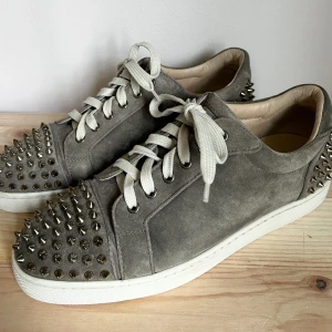 ÄKTA Christian Louboutin strl.43 - Säljer nu ett par äkta Louboutin skor i superfin gråbeige färg och med piggar både fram och bak.  Väldigt fint skick 9/10. Alla originaltillbehör medföljer, dustbag, extra snöre, piggar & kartong. Fler bilder och köpbevis kan skickas vid intresse.