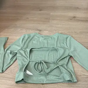 En ljus grön tröja med öppen rygg och slit på armen 