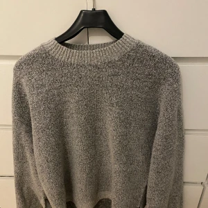 Grå stickad tröja  - Grå stickad tröja med knytdetaljer på ärmarna 