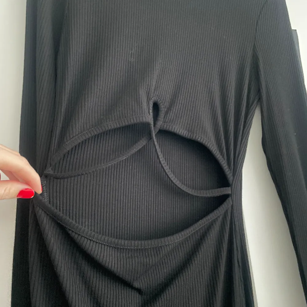 Säljer denna svarta klänning med lite detaljer på magen i storlek XS. Aldrig använd så prislappen är kvar . Klänningar.