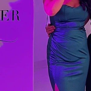 Grön satinklänning med slit nertill - Jättefin grön satinklänning som endast har använts 1 kväll. Passar väldrig bra för sig som kanske har bal eller ett kommande bröllop och inte har hittat en fin och elegant klänning ännu:)  Kemtvättad ( fläcken är vatten! )