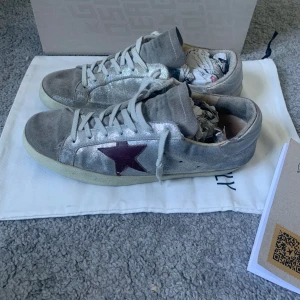 Grå Golden Goose Superstar - Säljer dessa silvriga/grå Golden Goose Superstar skorna! Skick: 7/10 (sulan lagad), Storlek: 40 (fits 40.5-41) nypris: 5600, mitt pris: 1299. Endast skorna medföljer. Är öppen för byten och hör av er vid frågor!💯