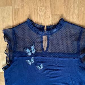 En blå stretchtopp med nät och tre broderade fjärilar från Orsay i storlek M. Längd 64 cm. Material: bomull. I normal begagnat skick.