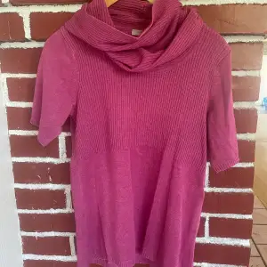Stickad, rosa tröja med korta ärmar och vid polokrage.  Cappuccini  Stl M