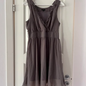 Fin klänning - Fin Grå klänning med benvit underklänning och benvit skärp till midjan om man vill. Tyllmaterial. Dragkedja i sidan