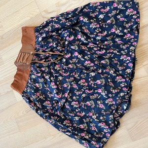 Blommog kjol - Blommig kjol motsavara M/L med lätt underkjol och brunt sydd typ bälte upptill