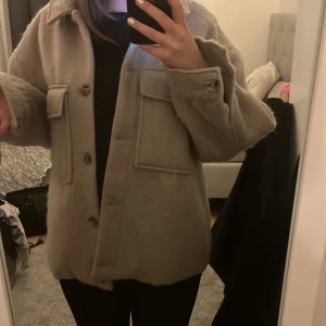 Kappa/jacka - Oanvänd ifrån ellos! Fin lite oversize men passar bra ändå på mig som har s i storlek! Man kan knäppa både vid händerna och längs framsidan av kroppen! Skulle nog tro att den passar de med storlek M med!