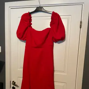 Röd midiklänning med många fina detaljer såsom puffärm, tajtare midja som sedan avslutas med en vid kjol.   - stor i storleken  - använd en gång