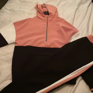 Set byxa och hoodie (svart, vit, rosa)  - Set byxa och hoodie i polyester, jättebra skick endast använt fåtal gånger