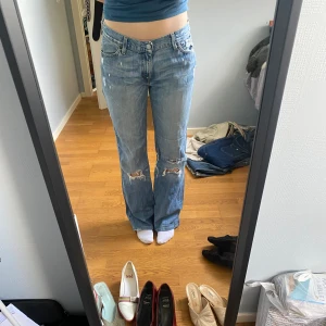 Lågmidjade bootcutjeans från Levis - Slitna lågmidjade bootcutjeans i ljusblått, perfekt till vår/sommar🌟 Passar s-m Är 165cm lång