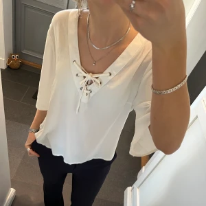 Trekvartsärmad vit blus - Vit trekvartsärmad blus med snörning från Flash Woman. Storlek M. Fint skick. Använd gärna köp nu!