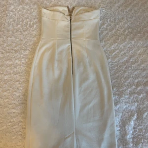 Vit klänning - Är i midi längd och axelbandslös med metalldetalj framtill. Köpte den till studenten men köpte flera och valde en annan, trots att denna var väldigt fin. Pris kan diskuteras!