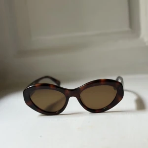 Chimi Solglasögon  - Solglasögon i fint skick med tillhörande fodral. The 09’s are the contemporary cat-eye sunglasses. Handcrafted from premium Italian acetate with flat lenses. Featuring the CHIMI logo engraved at the temples.  