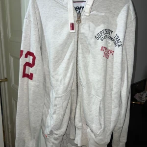 Vit/ljugrå melerad hoodie. - Hoodie från Superdry i storlek L. Jättefint skick. 