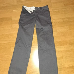Kostymbyxor - Gråa straight kostymbyxor från dickies, köpta här på plick. Dem har varit uppsydda i benen vilket man kan se. Övrigt jätte fint skick  Midjemått:76cm innerbenslängd:78cm totala längd:97cm Frakt tillkommer