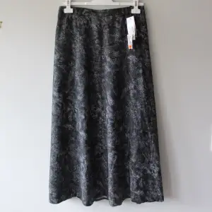 Mönstrad mörkgrå kjol från Cappuccini, storlek 42. Den har en underkjol. Helt oanvänd med prislappen kvar. Orginalpris: 499 kr. Reapris: 299 kr.  Midja (tvärs över): ca 38 x 2. Längd: ca 89 cm.