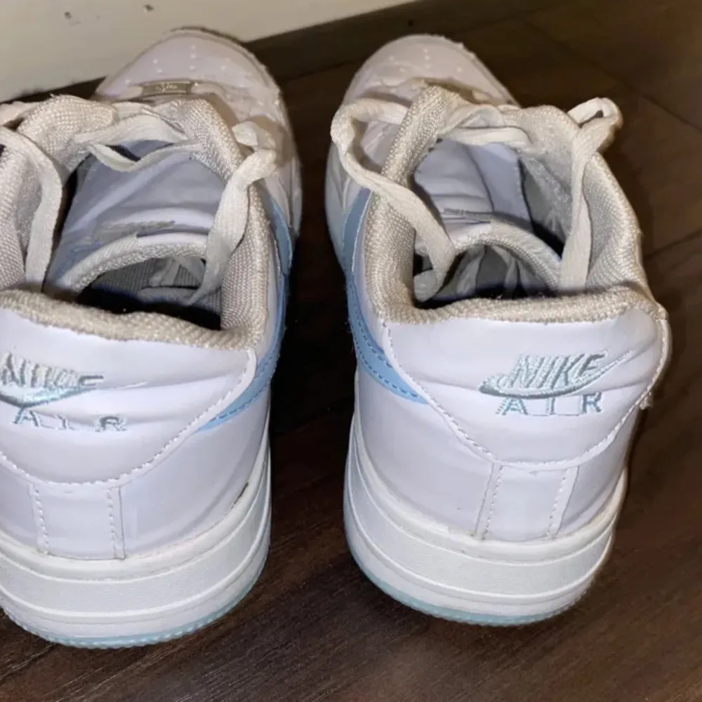 Vita Nike air force 1 sneakers med ljusblå logga och sula! Använda men i bra skick, storlek 39 Nypris 1600:-. Skor.