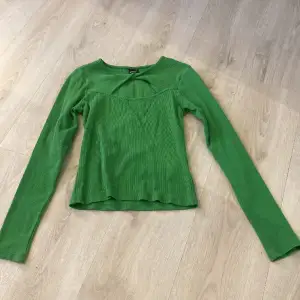 En grön tröja med öppen detalj vid halsen.  Från Ginatricot i storlek M. 
