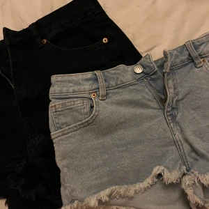 Jeansshorts  - Säljer två jeansshorts tillsammans, ett par svarta slitna med hål ish, ett par blå minishorts. De blåa är storlek 38 och de svarta är i xs men båda är väldigt lika i storleken ungefär samma