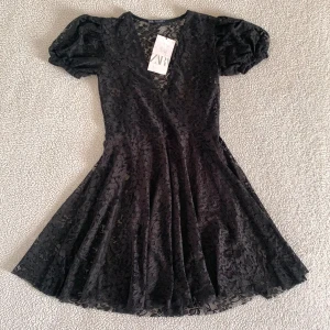 ZARA svart gullig spetsklänning  - Otroligt fin klänning från ZARA i spets. Finns en tunn underklänning på insidan. Ny med tags kvar, utan anmärkningar.