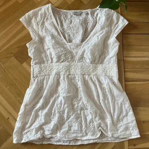 Vit topp - Vit somrig topp/ blus med söta blomsterdetaljer. Luftig med fin passform.  NEXT storlek 38