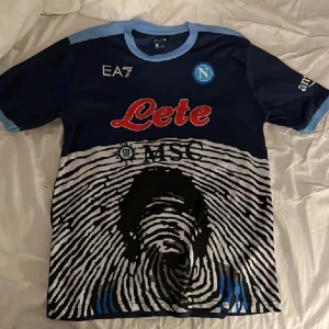 Maradona Napoli - En Napoli teöja med Maradona på ryggen. Mycket sällsynt tröja då det var limited edition. Storlek L. Är även ganska sällsynt