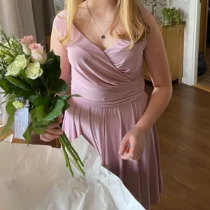 Rosa finklänning  - Säljer denna fina klänning. Använd endast en gång. Smutsrosa i glansigt material. Har sytt ihop överlappningen vid bröstet (se sista bilden)