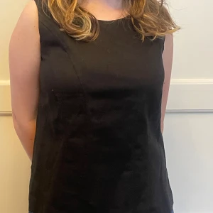 Elegant figursydd svart topp - Topp i lin/rayon, lite elastisk, snyggt skuren, sprund i sidorna, tvättas i 30 grader. Knappt använd, mycket fint skick.