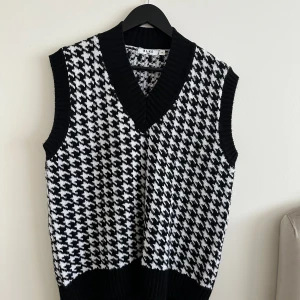 Stickad väst - En hundtandsmönstrad stickad väst i storlek M men passar S-L beroende på hur man vill att den ska sitta