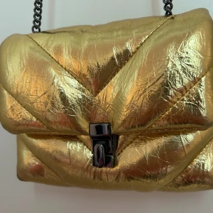 Axelremsväska  - Guldiga liten väska från zara. Inte använt mycke. Går o ha den längre o kortare.