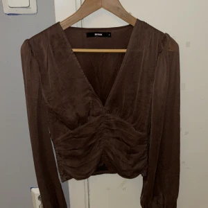 Blus - En brun blus från gina tricot som är oanvänd! Den är v-ringad i mesh liknande material