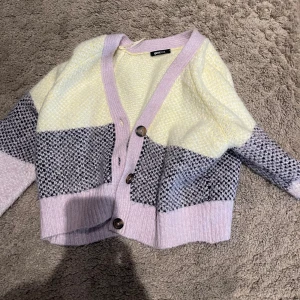 Stickad kofta-gina tricot  - Den är i storleken S fast man kan bära den också om man har i storleken M. Den är stickad och varm material. Tre olika färger gul,lila och en som är väldigt coolt färg svart och lila. Använt den 3 gånger 