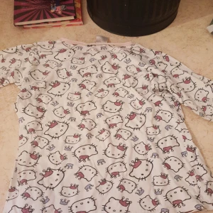 Den är vit med Hello Kitty på den är jättefin Det är en pyjamas - Det en vit tröja med Hello Kitty på Det är en pyjamas
