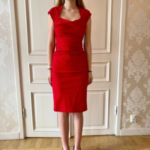 Röd klänning med rosett, Stop Staring! - Röd prickig klänning i stretchigt material. Storlek M. En knapp i bak saknas. Modellen på bilden är 173 cm och har storlek 38 i de flesta andra kläder. Aldrig använd. Vi har lagt ner vår klänningsbutik och säljer ut. Ny pris är 2000-3000kr