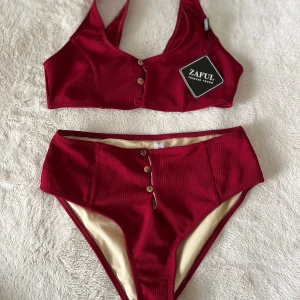 Mörkröd bikini - Helt oanvänd förutom provad en gång. Överdelen är för liten över bysten. Vilket är varför en av knapparna saknas.. kan laga om så önskas.⚒️ Underdel med hög midja & high cut. Köpt från Zaful för 6 år sen 💕 Skriv för fler bilder. Pris kan diskuteras ✉️