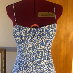 Blommig sommarklänning - Lätt och somrig klänning som bara är använd en gång. Passformen är superfin och midjan går att justera. Den har en slits på ena benet från ungefär halvvägs ner på låret. Nypris: 399 