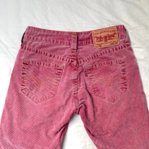 Levis rosa manchesterbyxor  - Rosa manchesterbyxor från Levis. Lätt utsvängda och låga i midjan. Har en liten fläck som visas på bild, för övrigt i mycket fint skick. Pris kan diskuteras!