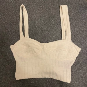 Ribbstickad topp /linne - Söt liten topp som är ribbadstickad i benvit färg , helt ny! (Aldrig använd) Storlek xxs upplevs som s 