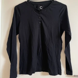 Pyjamas tröja - En svart långärmad pyjamas tröja med knappar i kragen