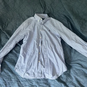 Ralph Lauren skjorta  - Blå rutig Ralph Lauren Skjorta i mycket bra skick. Knappt använd. Storlek är 20 år. Skulle säga att det passar en S-lite mindre M. 