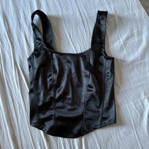 Fest topp - Jättesnygg glansig fest topp som är något längre fram än bak. Stl xs 