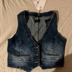 Jeansväst i storlek S - Jag säljer denna fina jeansväst då den tyvärr är för liten för mig och bara har legat i garderoben.Den är aldrig använd