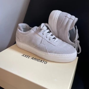 Axel Arigato  - Säljer nu mina Axel Arigato Light Grey i storlek 40. Dom är i väldigt fräscht skick pga inte använda mycket. Perfekt till dig som vill ha en fräsch stil i sommar